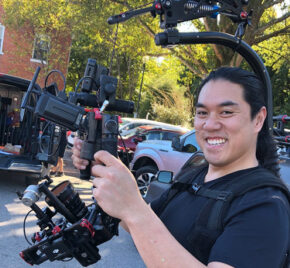 Anthony Tran smiling while operating a camera rig on a video shoot.