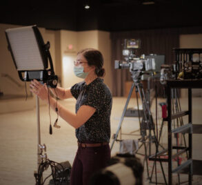 Emily Morris, motion graphic designer of Kino Mountain Productions, adjusting a light on the set of a video shoot in Wake Forest, NC.